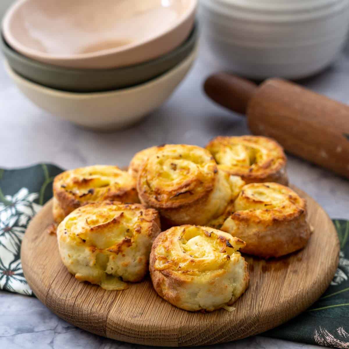 A close up of scrolls stacked on a round wooden chopping board.