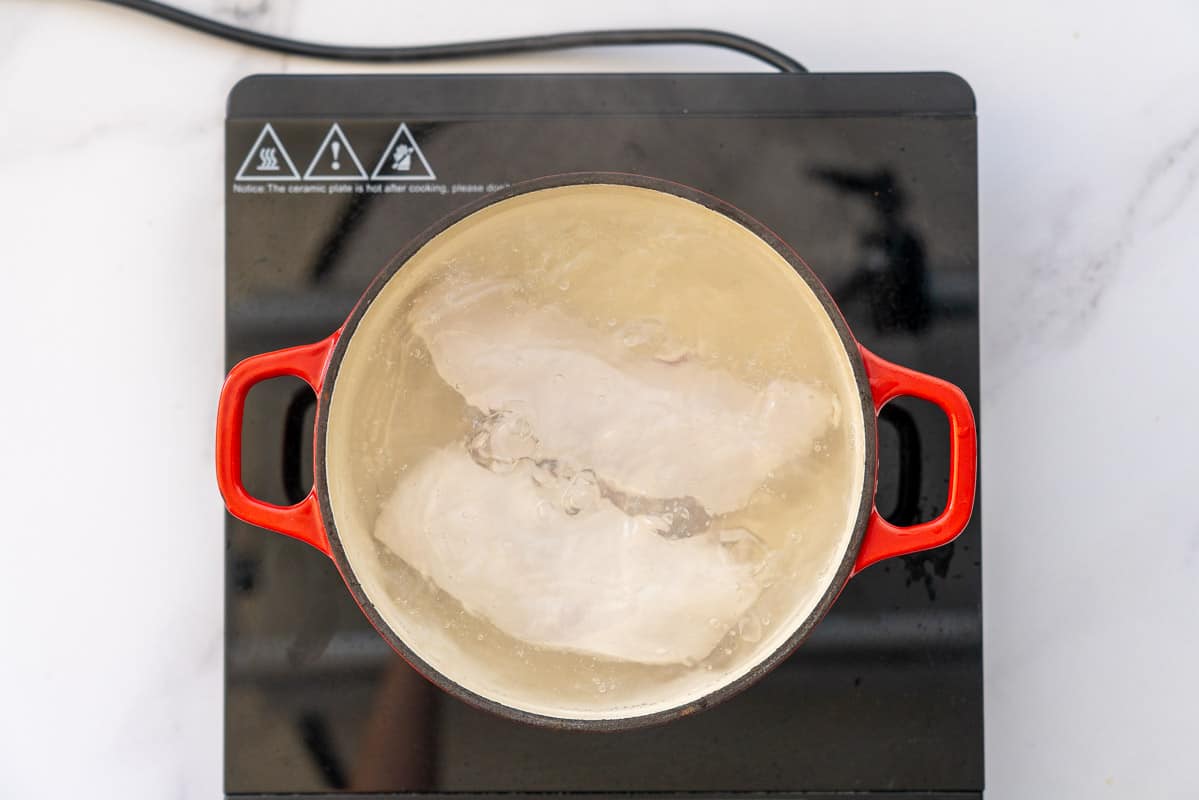 Chicken breasts in a pot of water on an induction element.