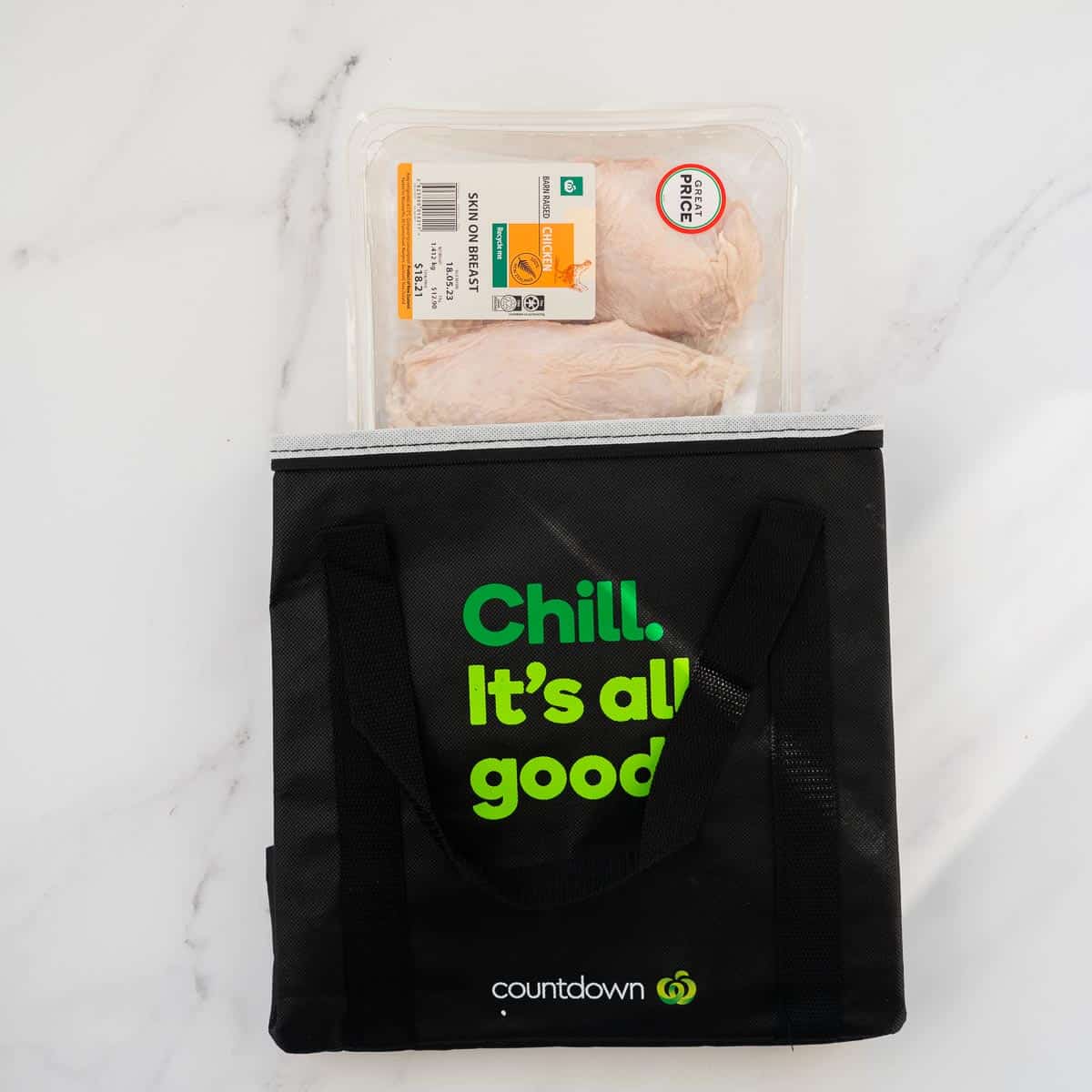 A large pack of chicken breasts with skin on, in a supermarket cooler bag.