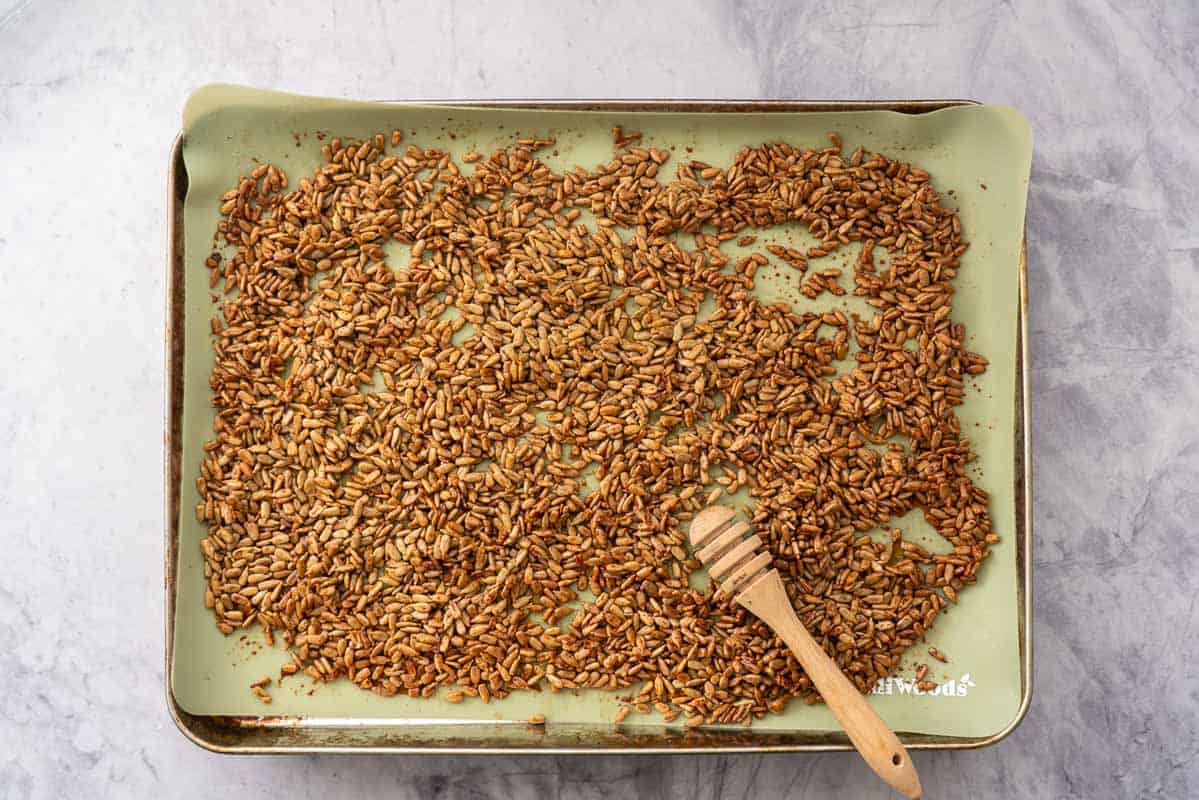 Over tray with a green silicone liner with the coated sunflowers and the honey dripper stick