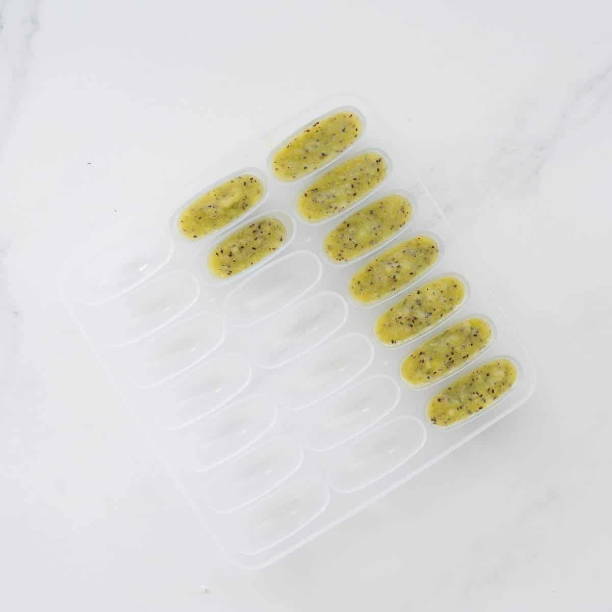 Pureed kiwi in a baby food freezer tray ready to go into the freezer.