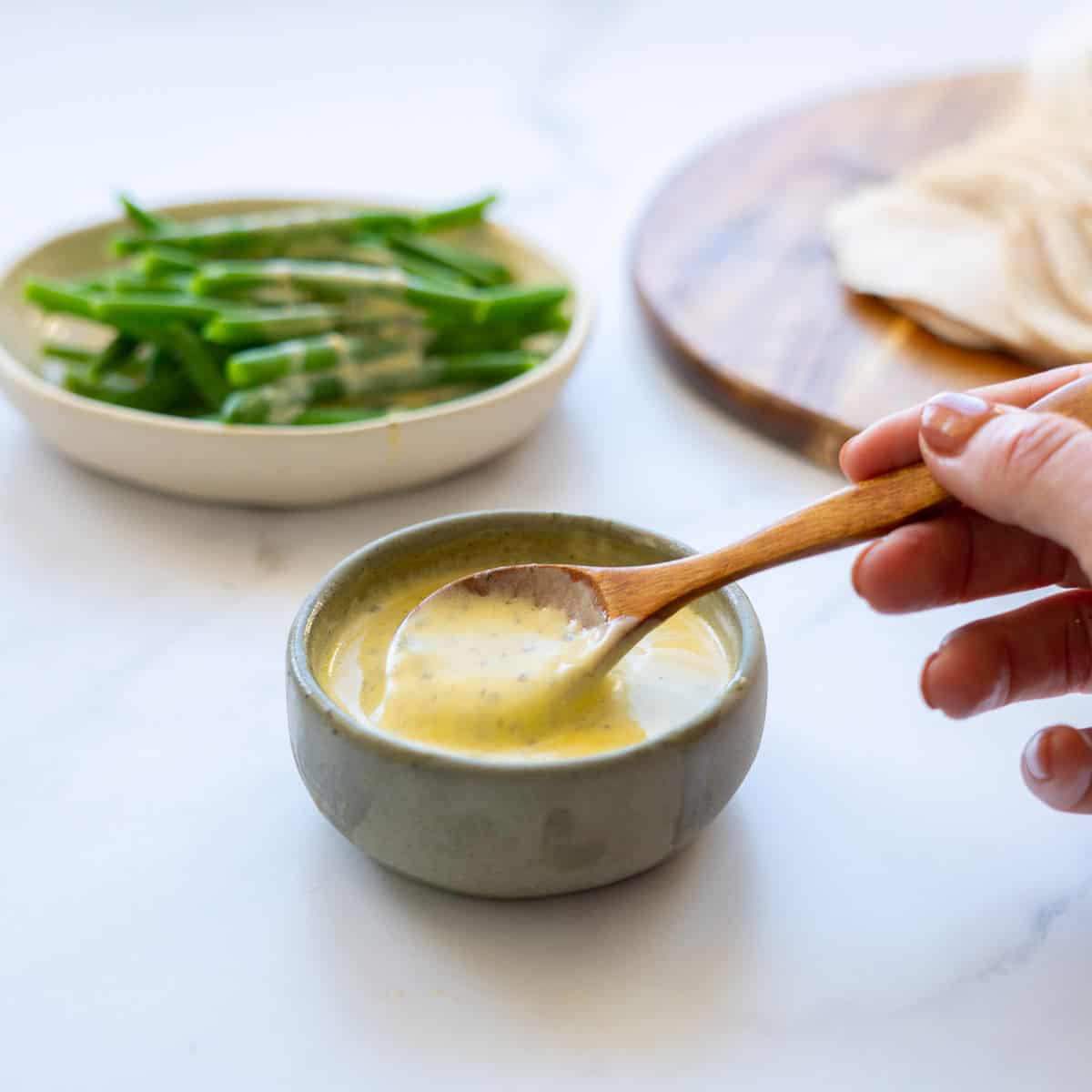 Lemon cream sauce being spooned from a green ceramic ramekin.
