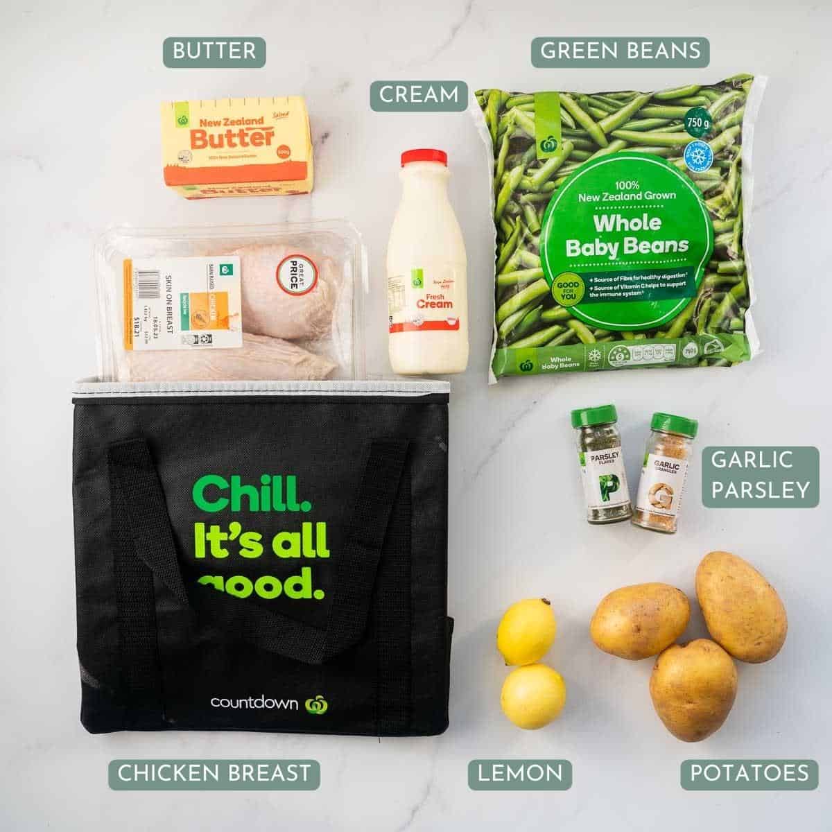 The ingredients to make a poached chicken dinner laid out on a bench top with text overlay.