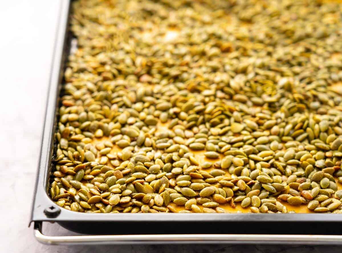 Close up of toasted pepitas on a baking sheet.