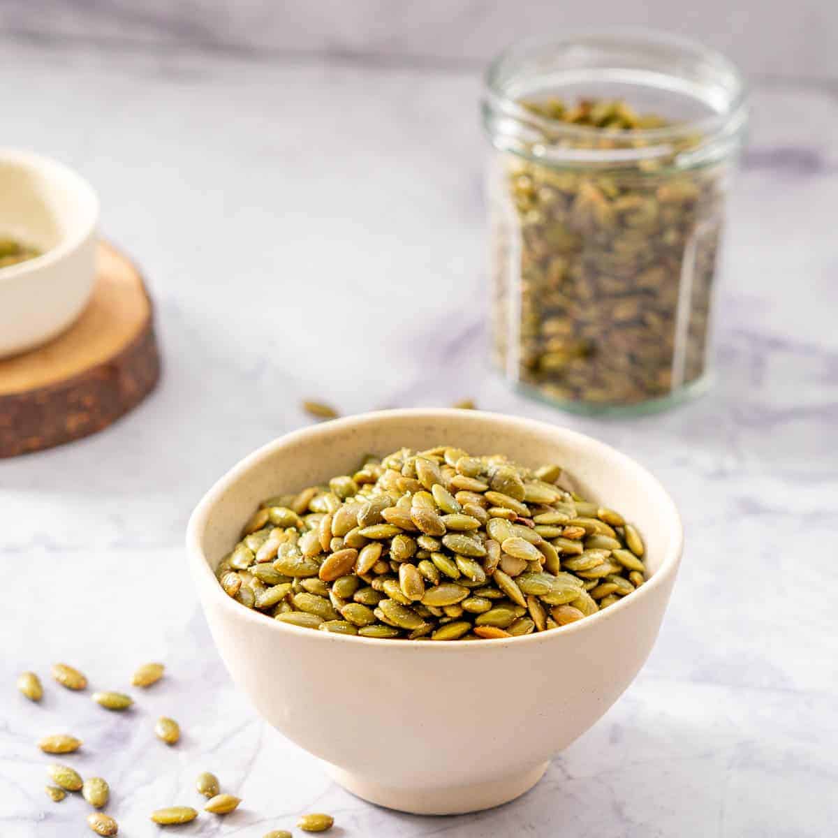 A small ceramic bowl filled with roasted pepitas.