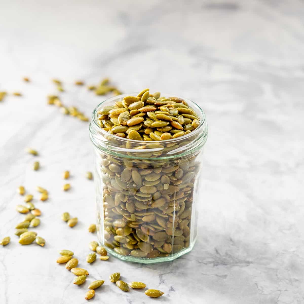 A glass jar filled with roasted pepitas