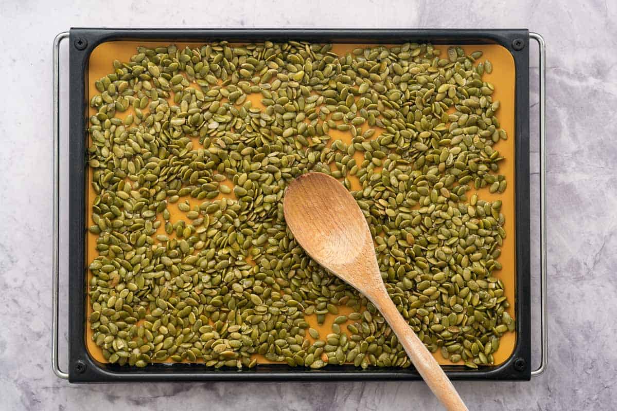 Oven tray with tan silicone mat with seeds ready to roast.