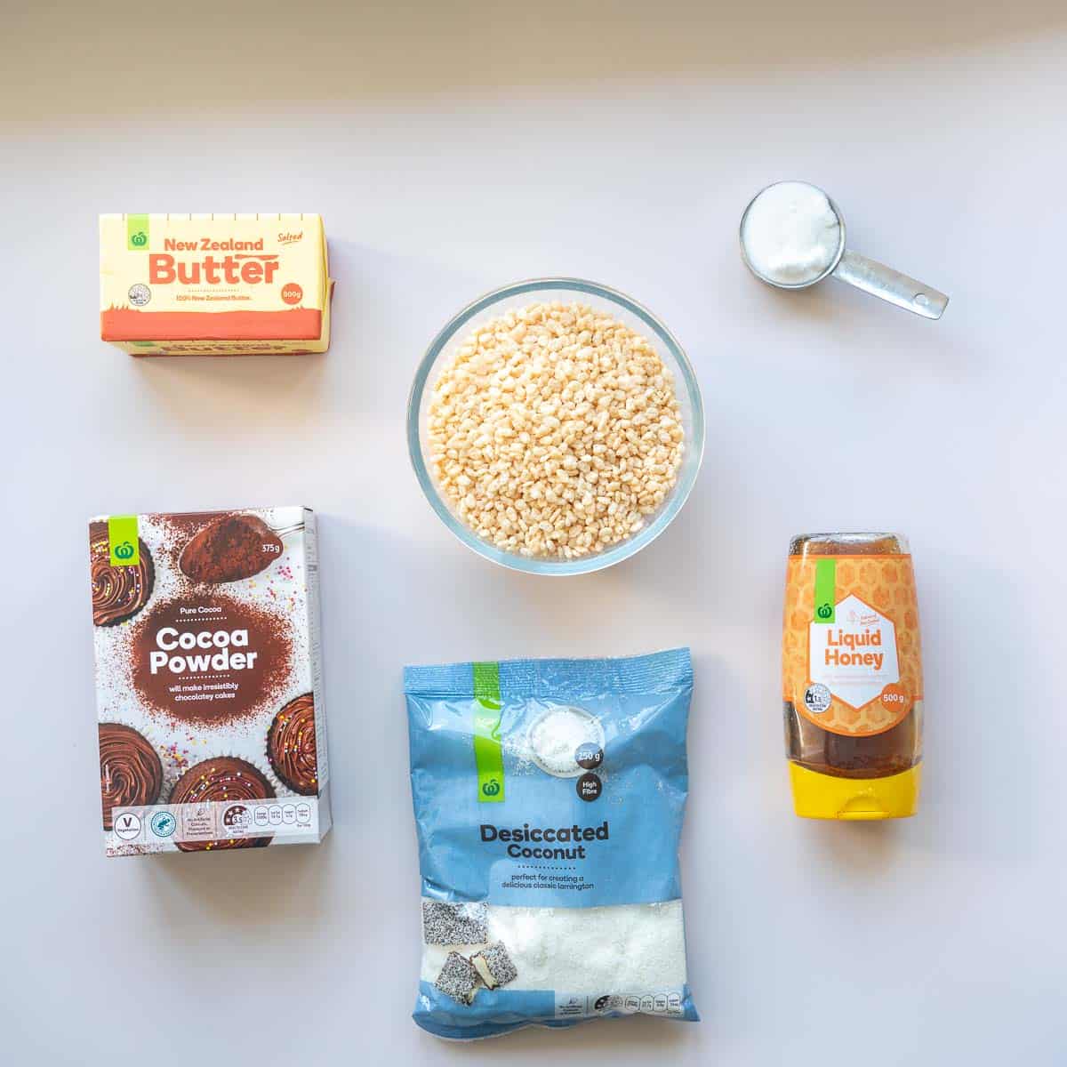 butter, puffed rice, honey, cocoa, sugar and desiccated coconut laid out on a bench top