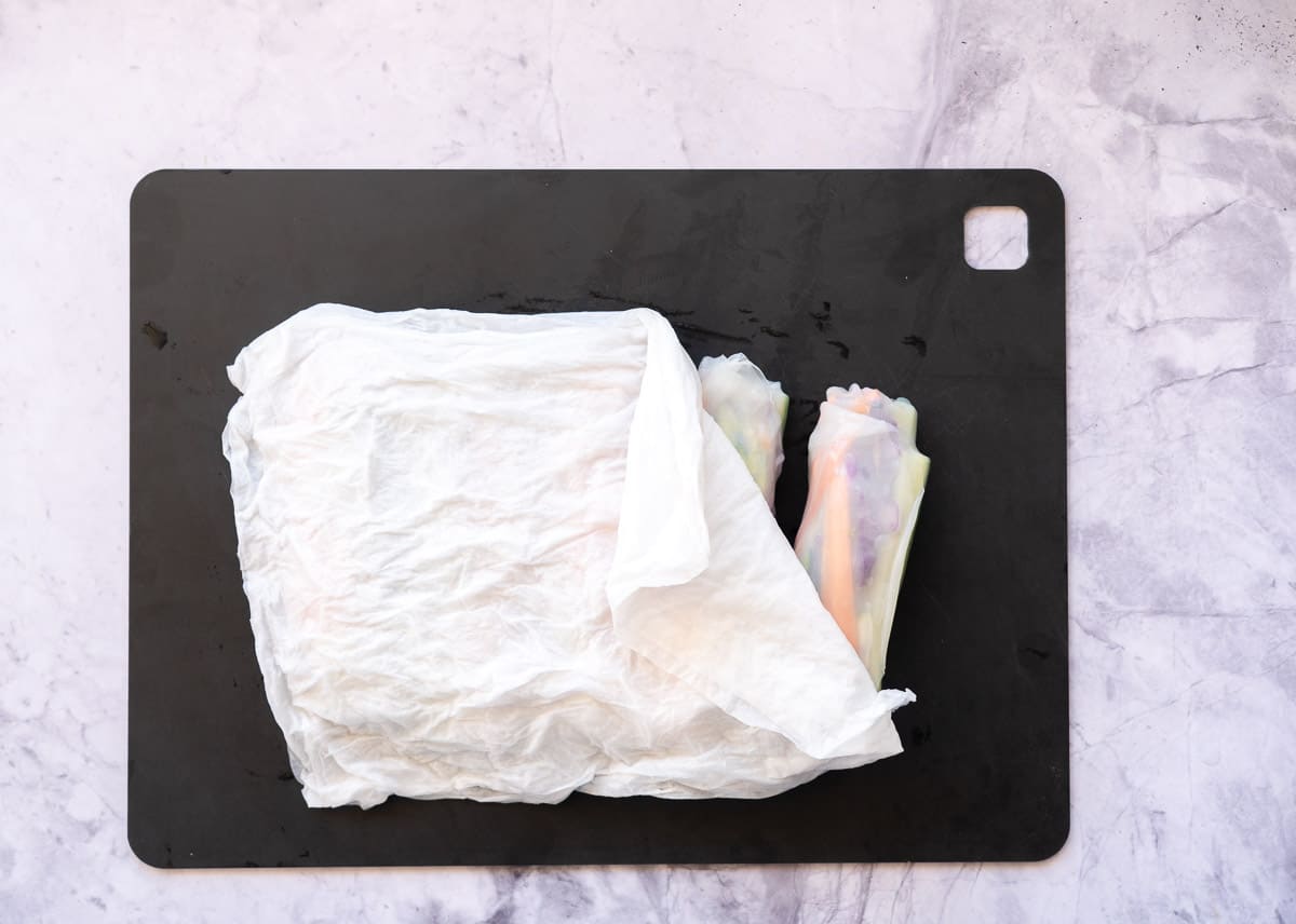 Rice paper rolls covered by damp paper towels.
