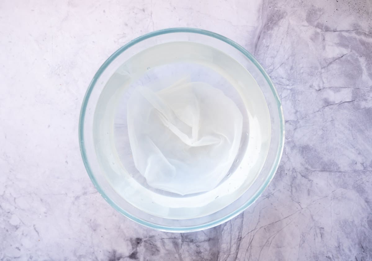 Rice paper in bowl of water on bench top.