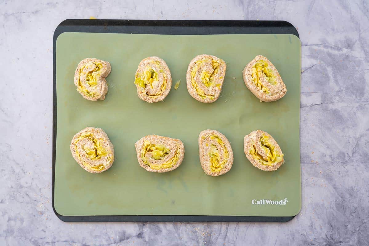 8 scrolls on a baking sheet lined with a green silicone liner.