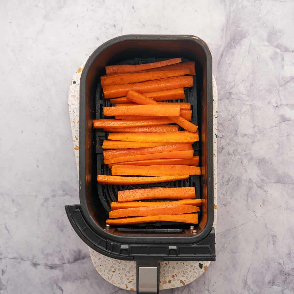 Carrot sticks in an air fryer basket.