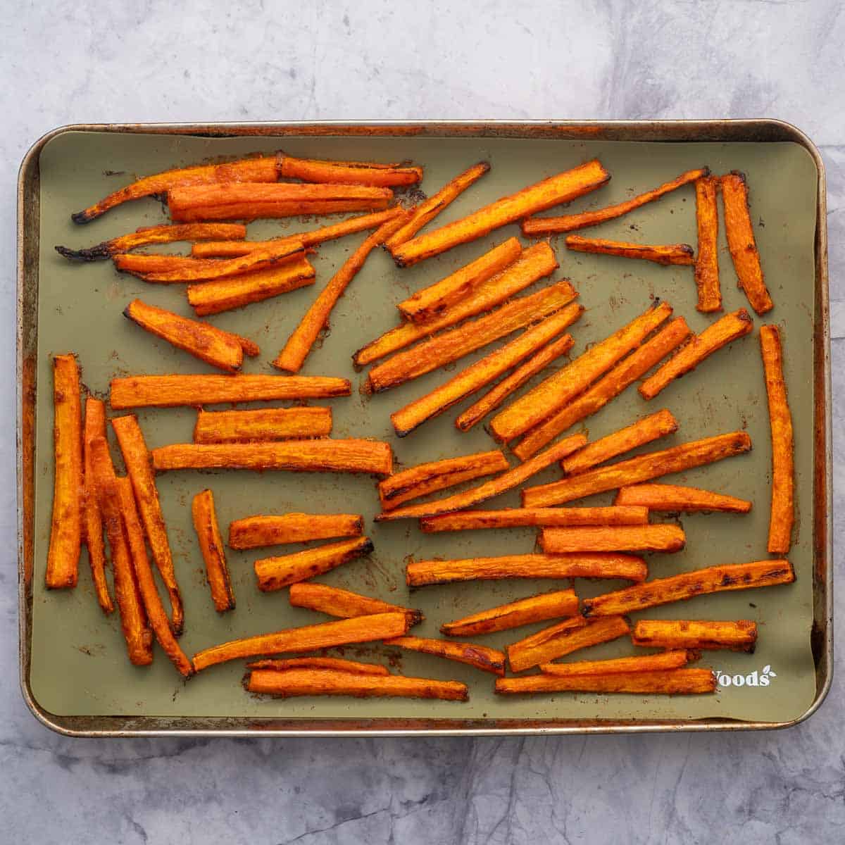 Carrot fries on a line baking sheet, ready for seasoning.