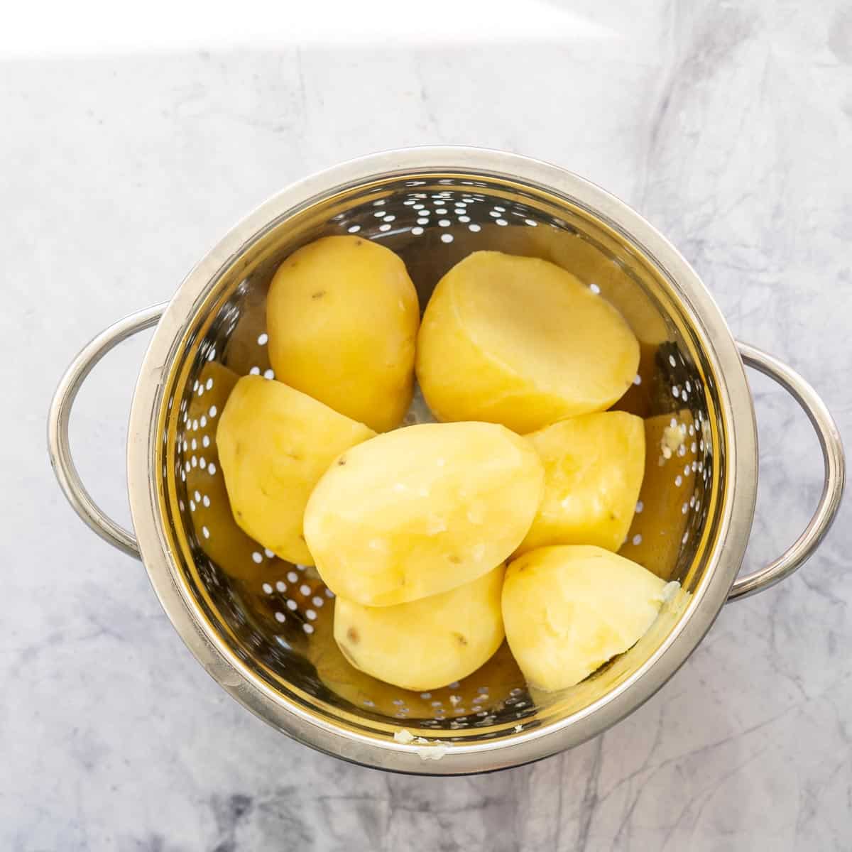 Large cooked potatoes in a colander.
