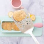 A baby pancake being held up to the camera on a stainless steel spatula.
