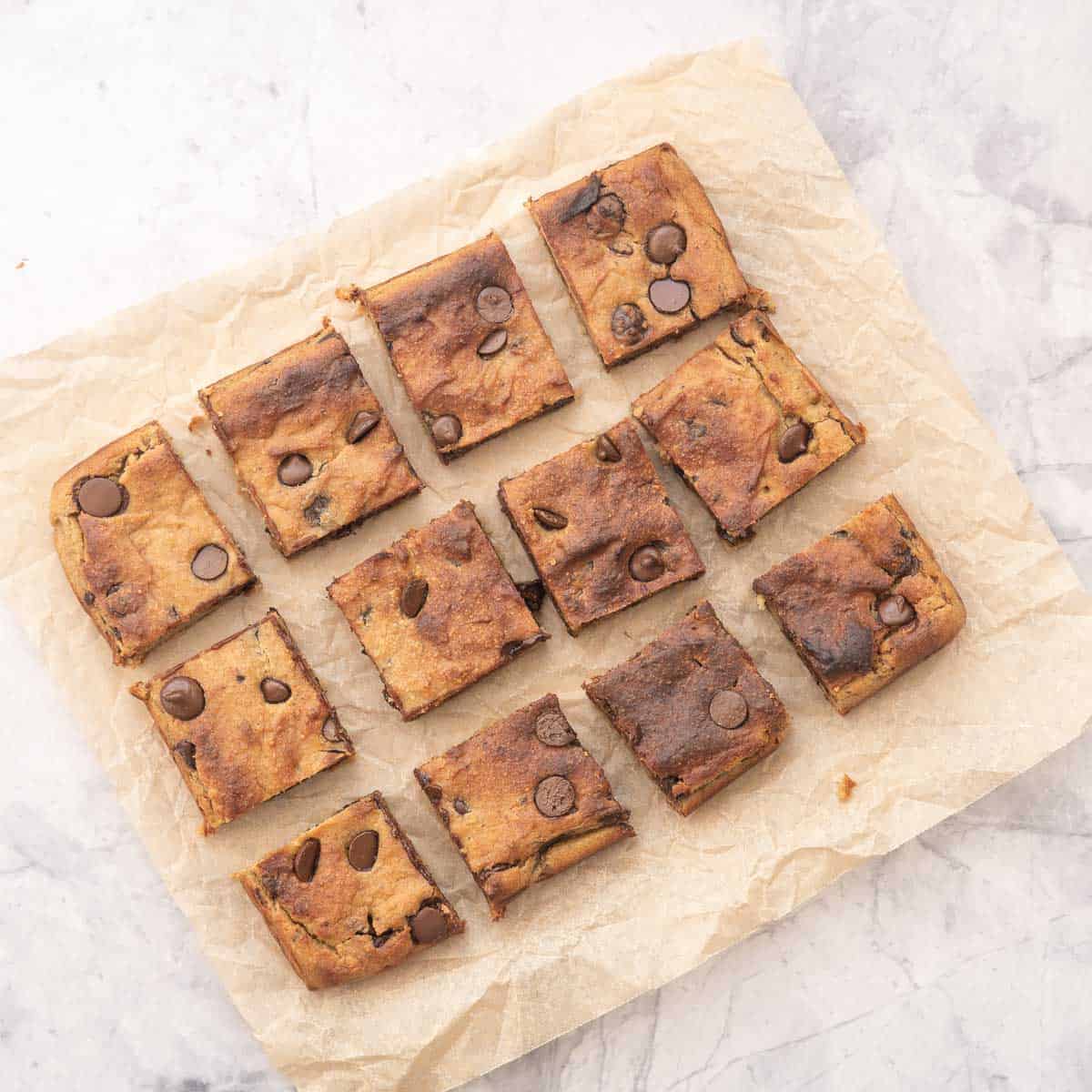 Baked Chickpea Blondies sliced and sitting on brown crinkled baking paper