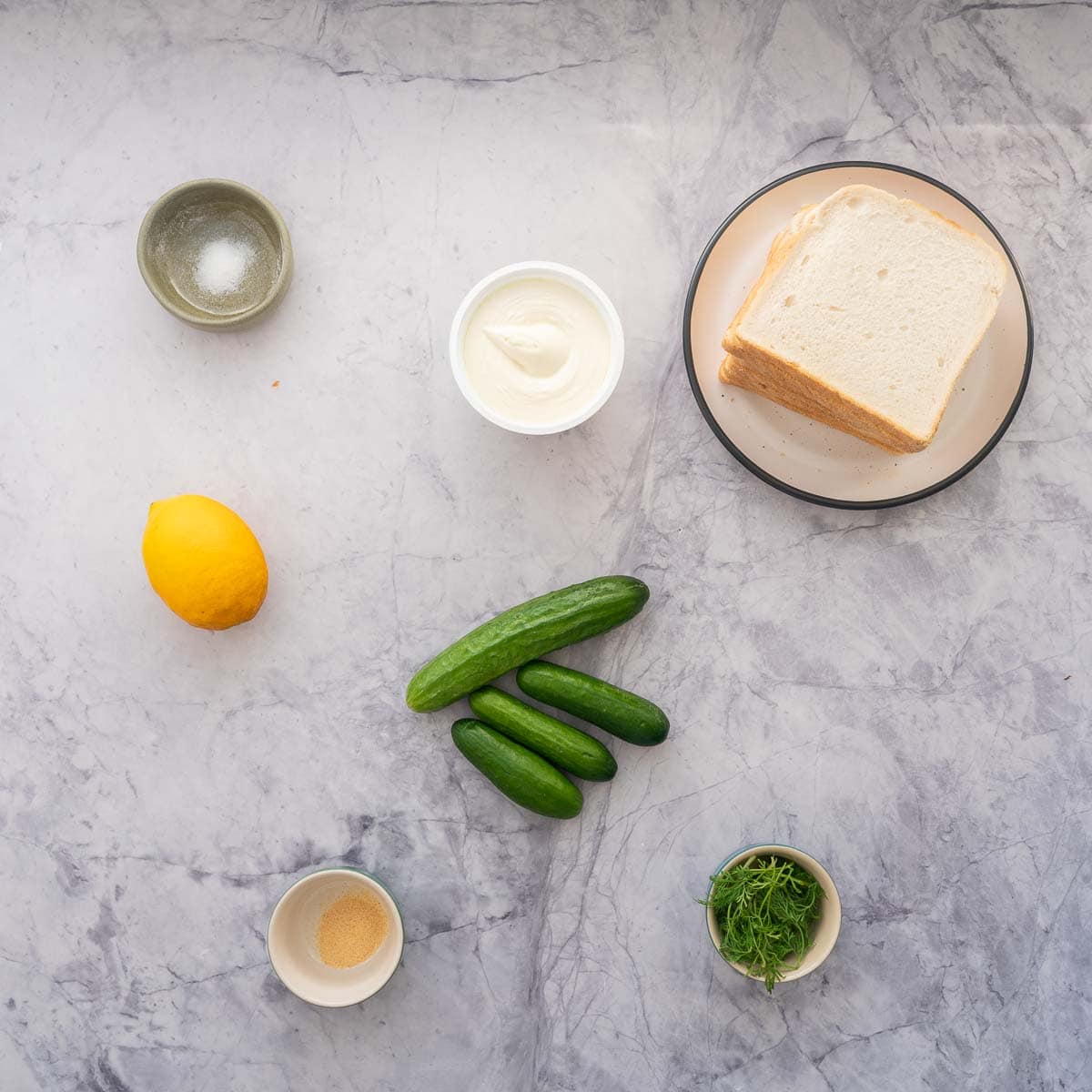 Ingredients for cucumber sandwich laid out on bench top.