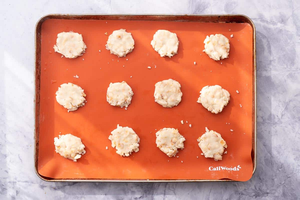 Lined tray sitting on the bench with 12 cookies pressed down