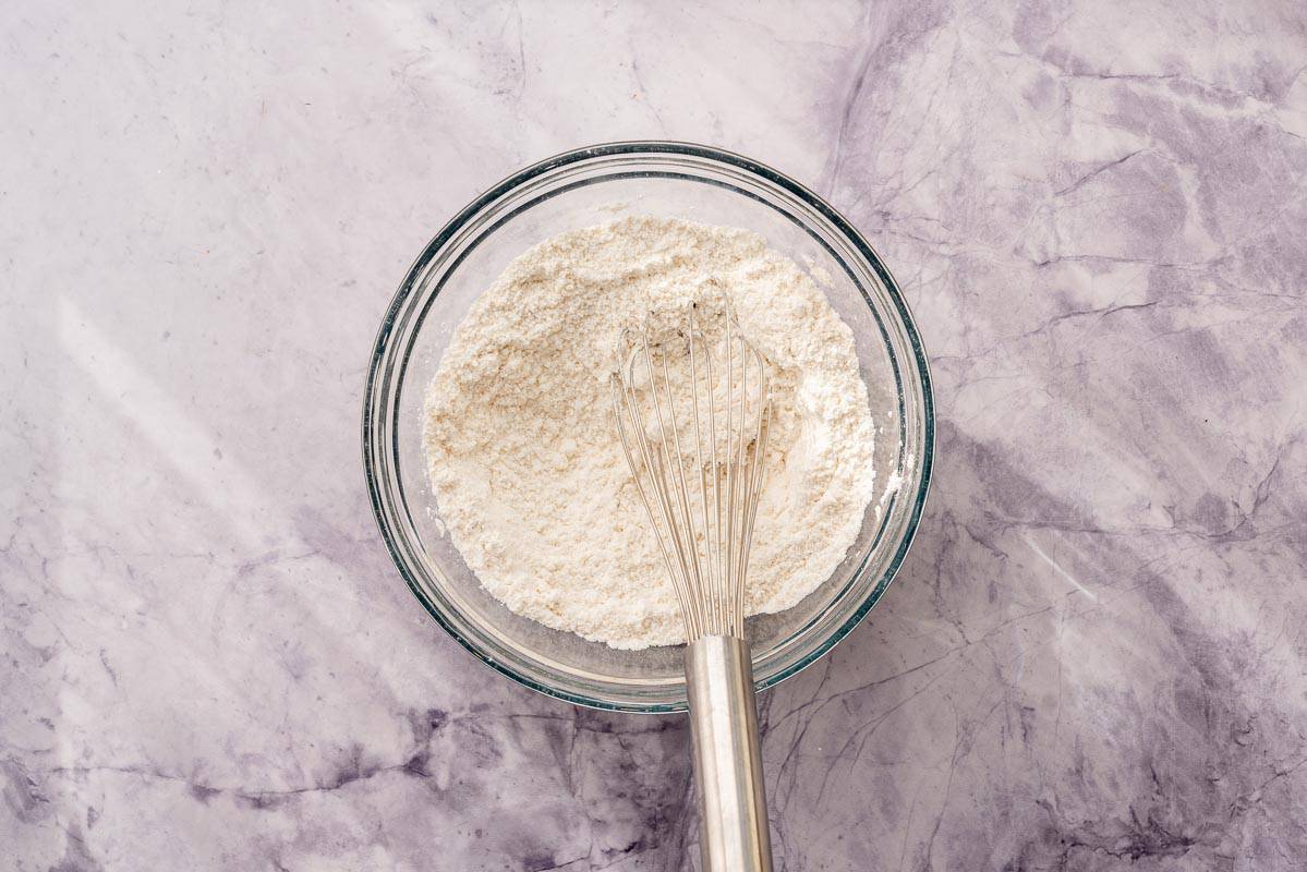 Dry ingredients in a bowl with a whisk sitting on the bench