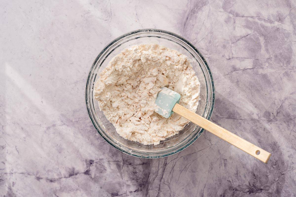 Dry ingredients including the toasted coconut in a bowl with a whisk sitting on the bench