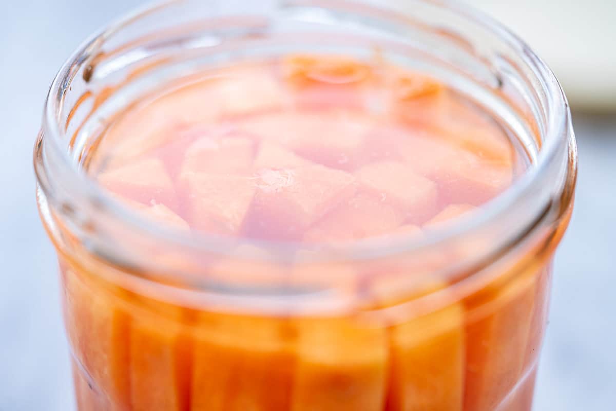 One jar of battened, pickled carrots sitting on the bench