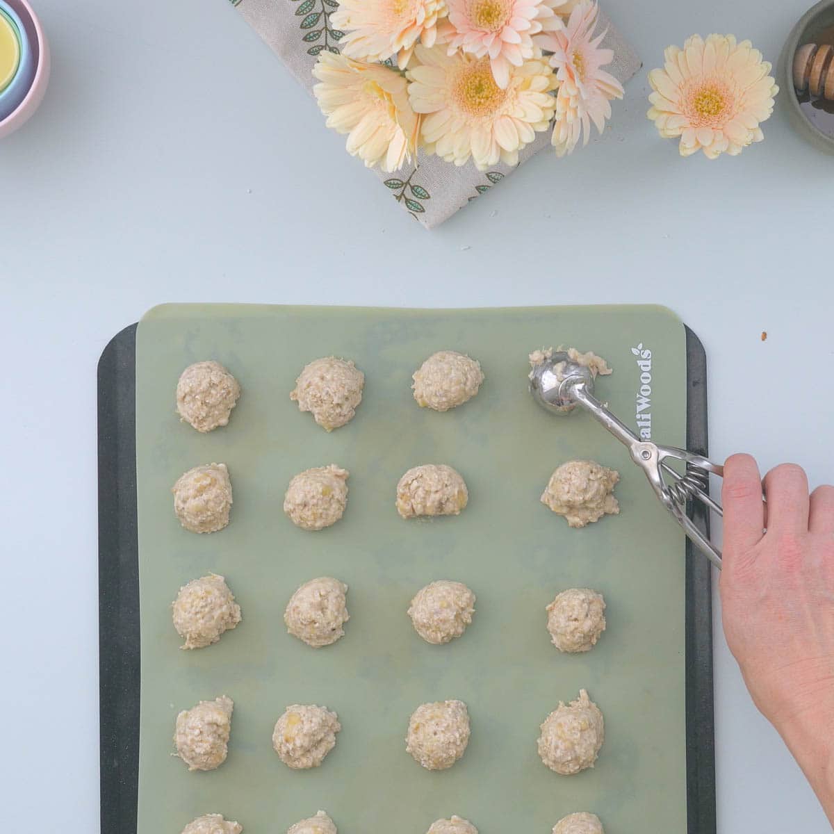 Scoops of oat cookie dough on a green lined tray.