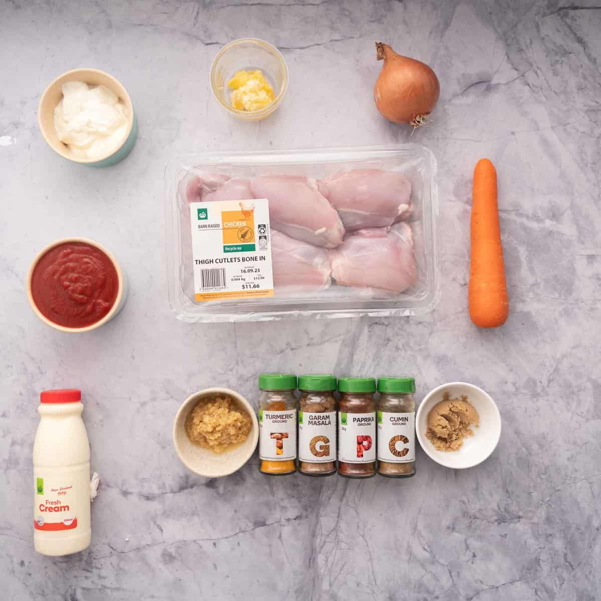 A bench filled with all the ingredients to make the Butter Chicken, cream, spices, sugar, ginger, tomato puree, carrot, onion, ghee and yoghurt.