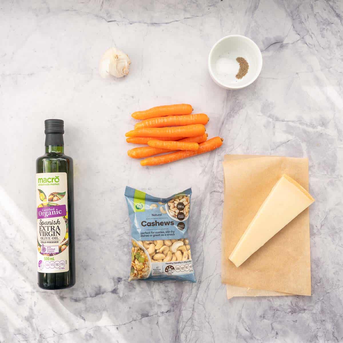 The ingredients to make carrot pesto laid out on a bench top.