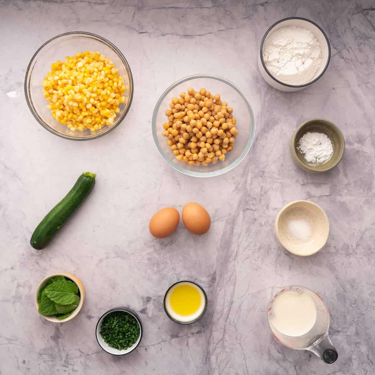 Small dishes sitting on a bench filled with ingredients to make the chickpea fritters