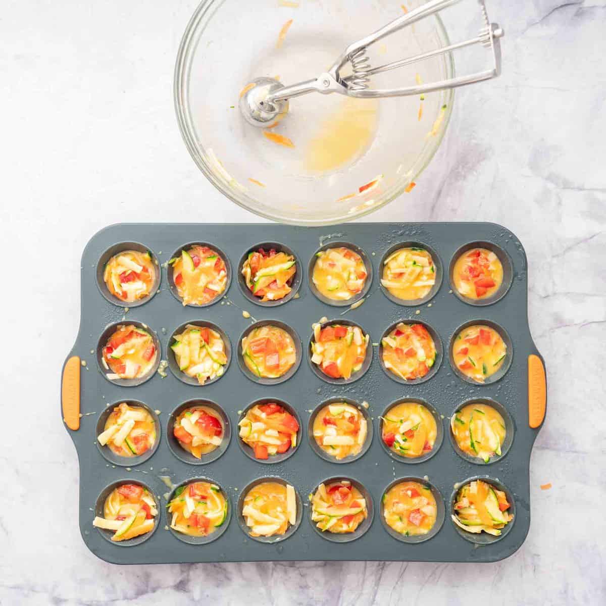 Egg and vegetable batter in a mini egg muffin tray.
