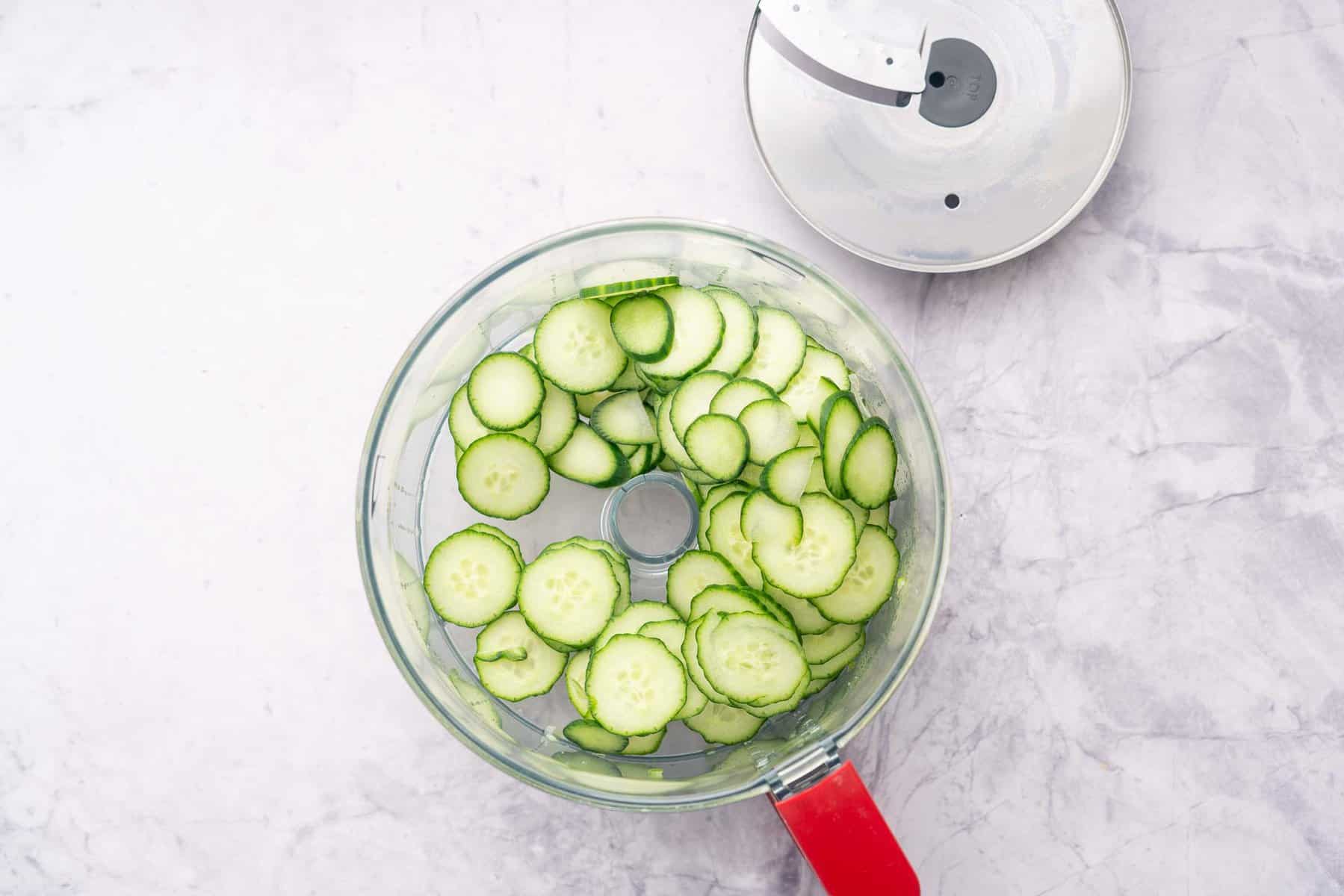 Sliced cucumbers in a food processor with lid off.