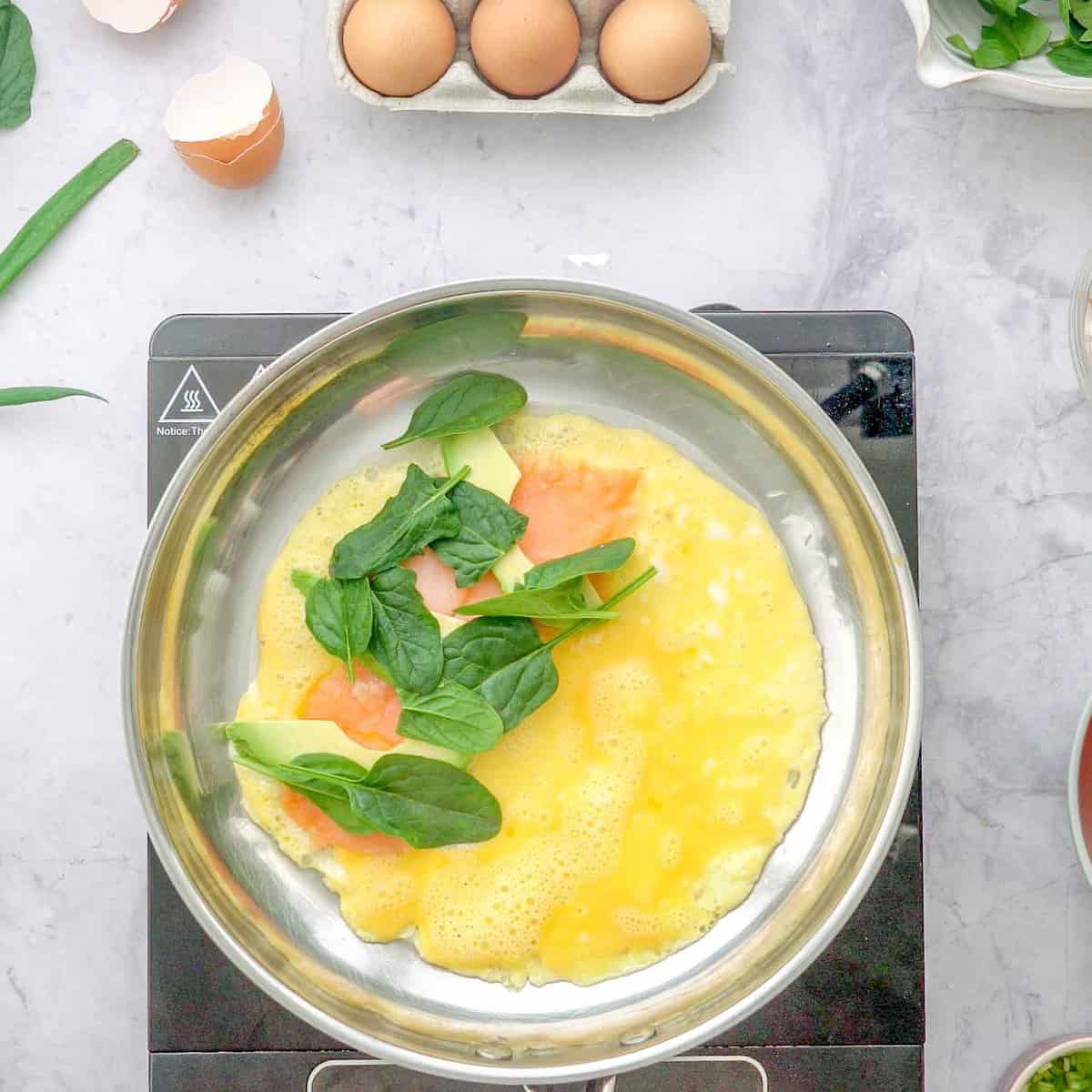 Spinach, salmon and avocado on one half of omelette.