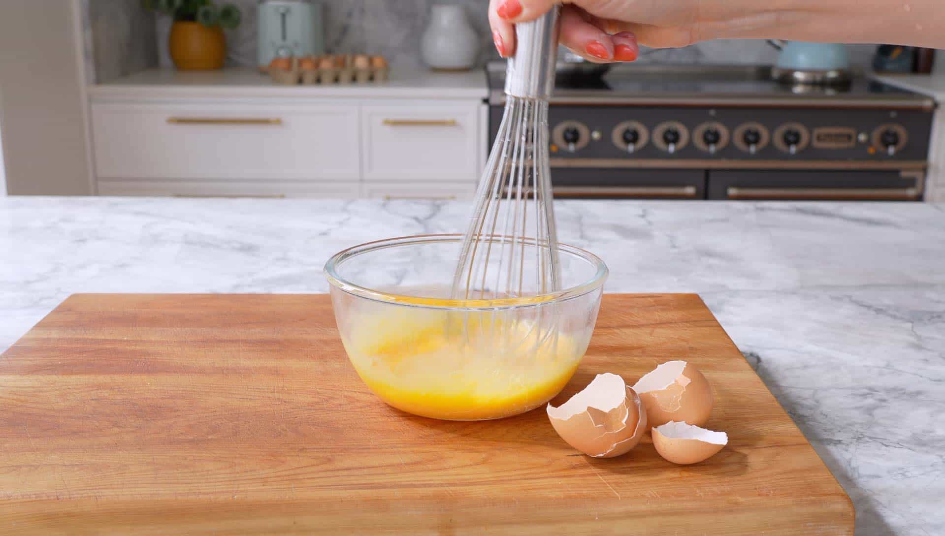 Eggs being whisked together in glass bowl.