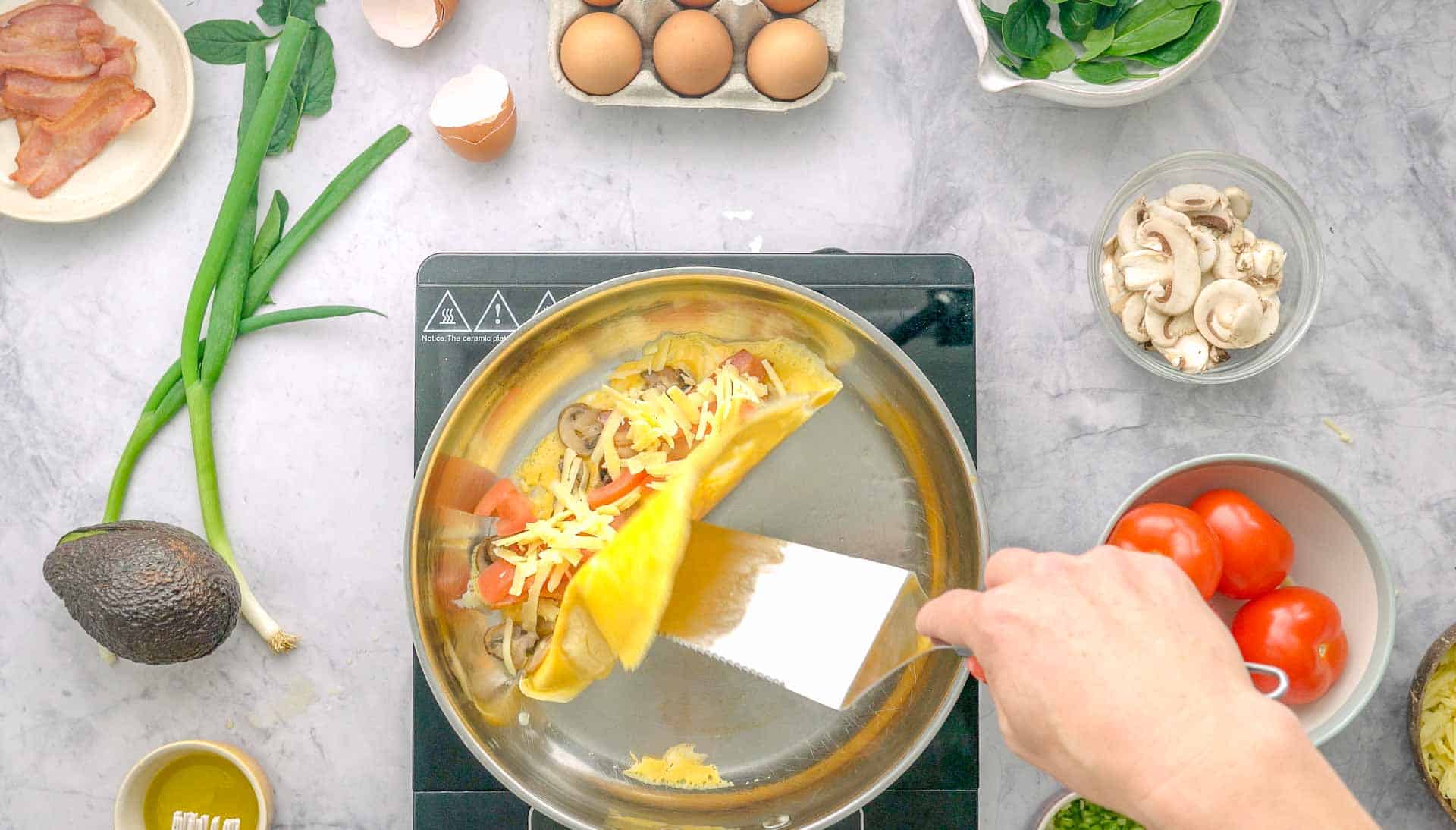 Spatula flipping omelette in half with ingredients inside.