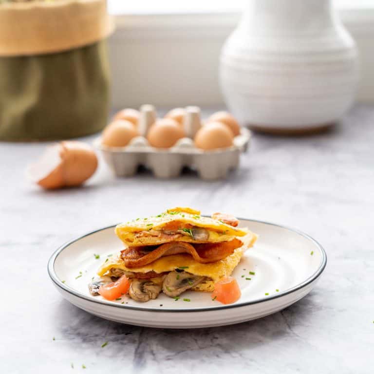 A rice paper omelette on a side plate on a marble bench top.