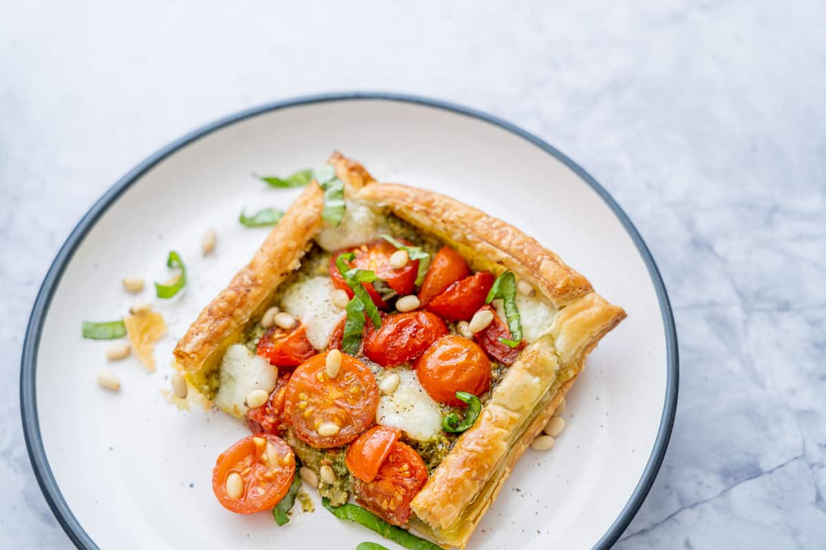 A piece of tomato tart cut and served on plate.