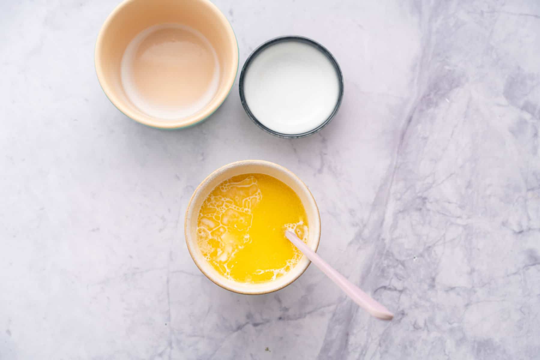 Emptied ramekins next to the mug full of ingredients with a stirring spoon in it.