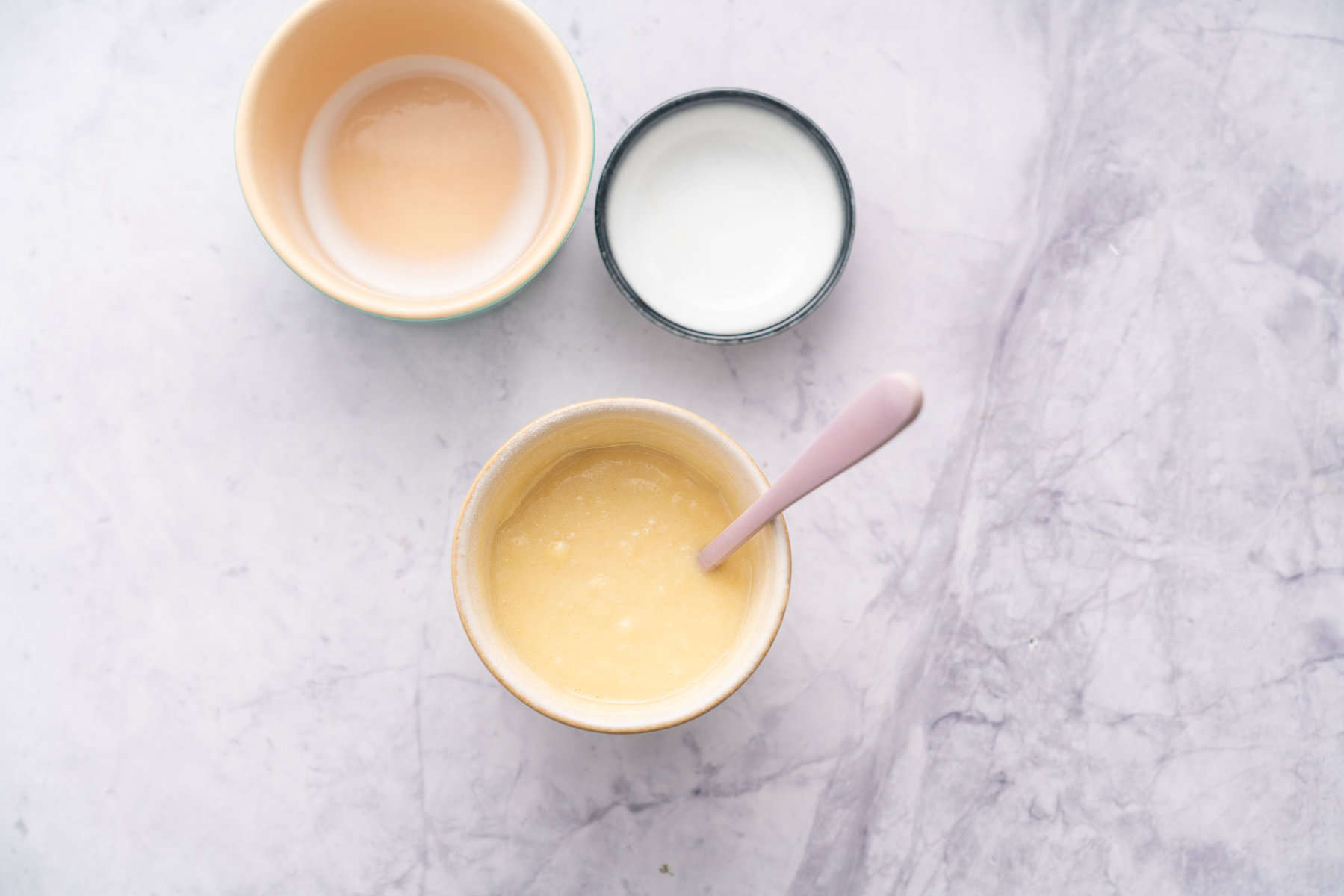 Emptied ramekins next to the mug full of ingredients with a stirring spoon showing everything fully mixed