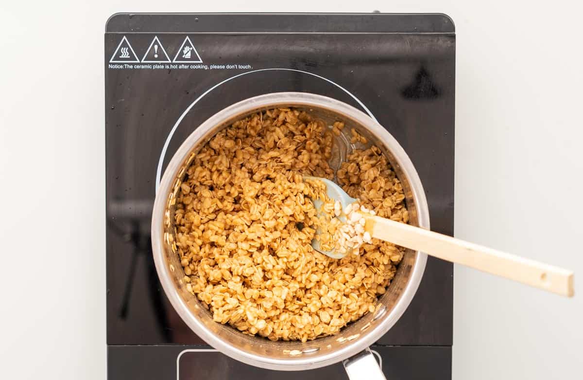 Puffed rice cereal and rolled oats combined with a peanut butter caramel in a saucepan
