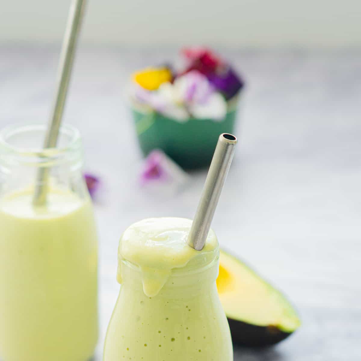 Two glass jars filled to the brim and slightly overflowing with a metal straw in each one.