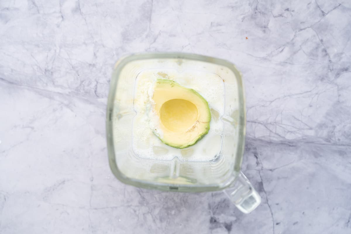 Two large all the ingredients placed in a blender sitting on the bench