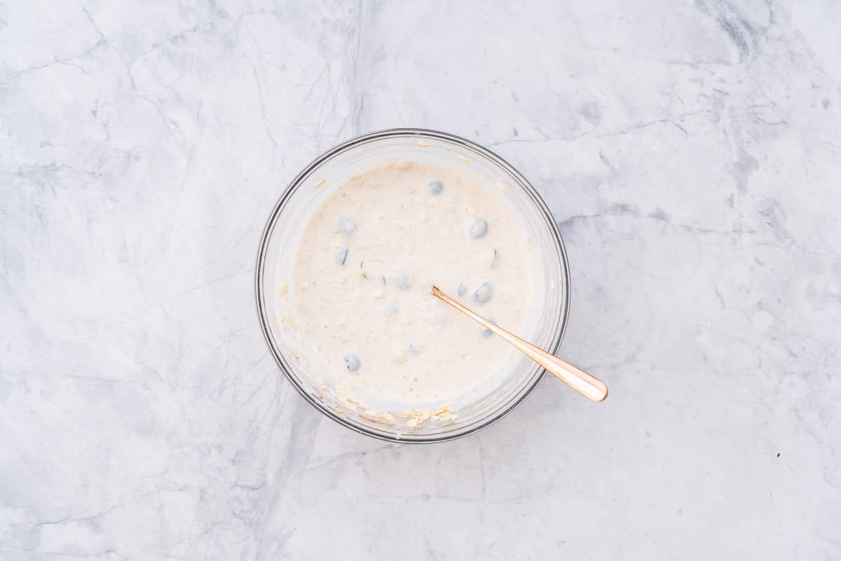 All the ingredients combined in a glass bowl sitting on the bench with a brass spoon.