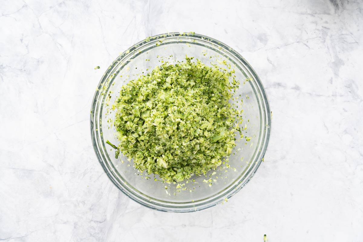 A large glass bowl full of steamed and blitzed broccoli sitting on the bench.