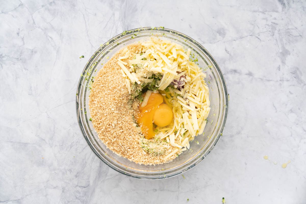 Remaining ingredients added to the glass bowl of blitzed broccoli sitting on the bench
