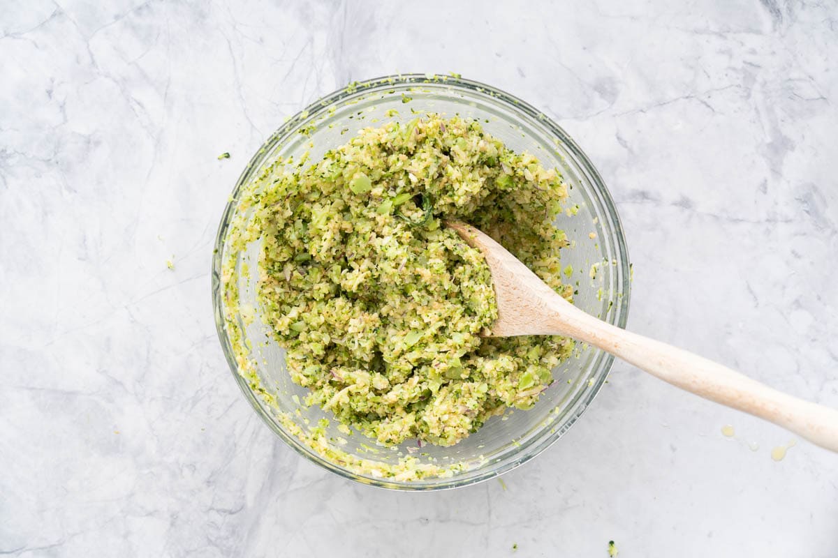 Large glass bowl with ingredients all stirred together by a wooden mixing spoon
