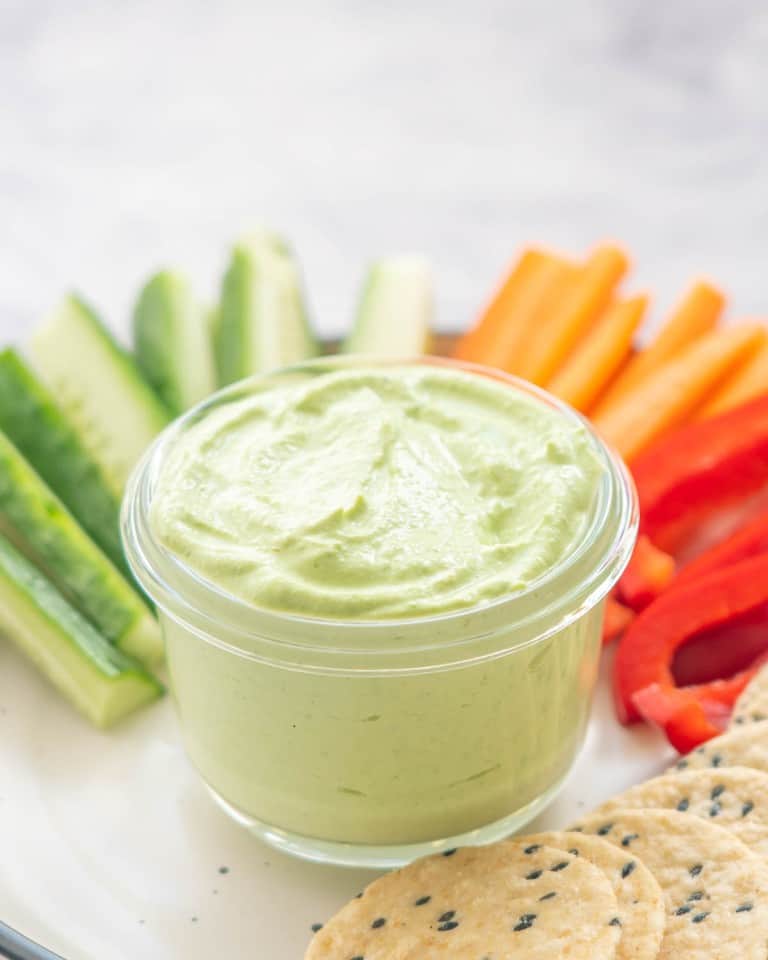 A glass bowl filled with a creamy green dip.