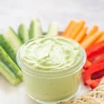 A glass bowl filled with a creamy green dip.
