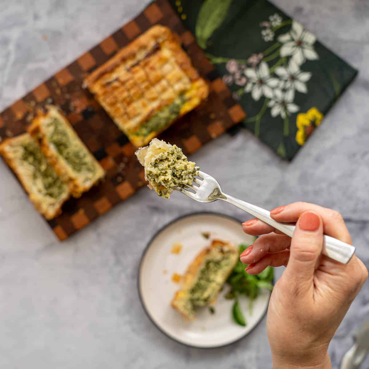 A forkful of spinach cheese pie filling being held up to the camera.