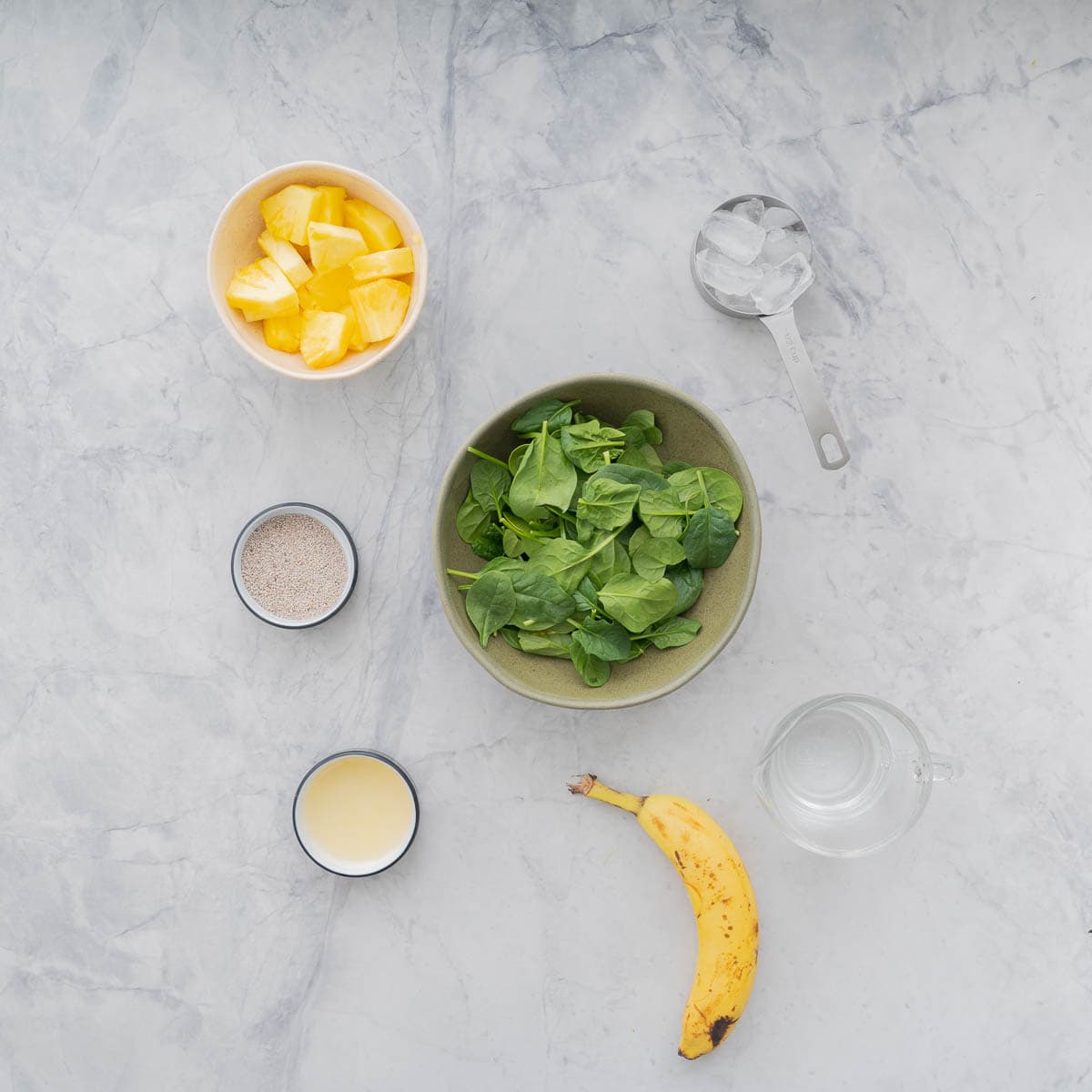 All the ingredients to make a spinach smoothie laid out on the bench.