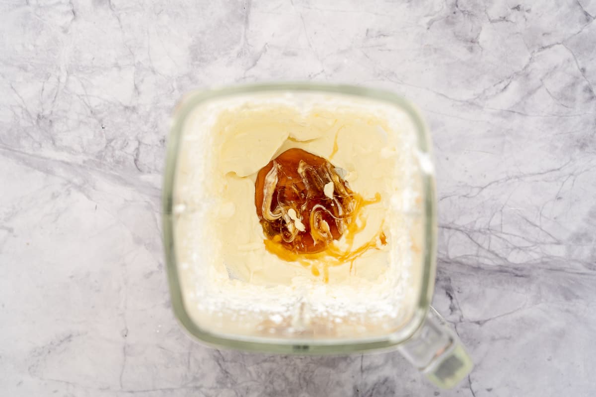 A blender full of whipped cottage cheese with a good drizzling of honey added to it sitting the bench